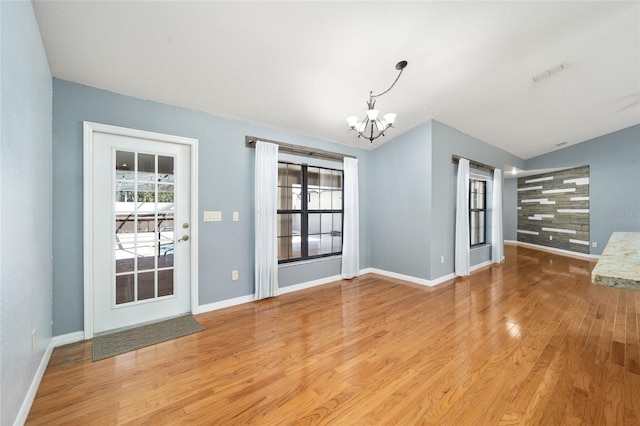 unfurnished living room featuring vaulted ceiling, an inviting chandelier, and light wood-type flooring