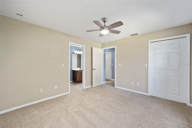 unfurnished bedroom featuring ceiling fan, ensuite bathroom, a closet, and light colored carpet