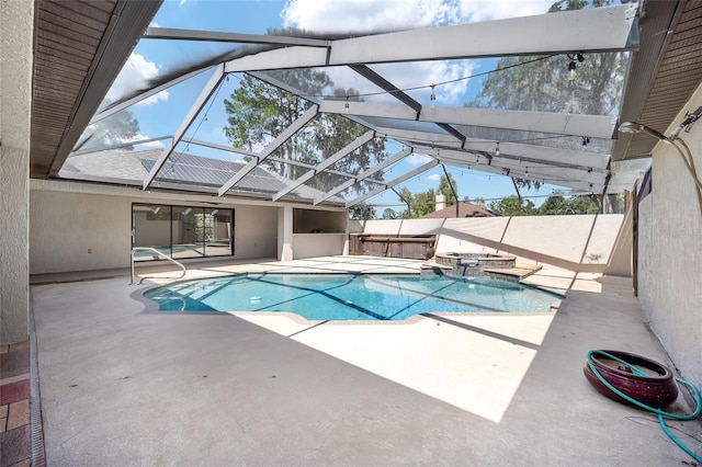 view of swimming pool with glass enclosure, a patio, and an in ground hot tub