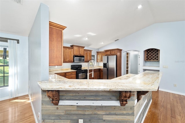 kitchen with a kitchen breakfast bar, kitchen peninsula, lofted ceiling, and stainless steel appliances