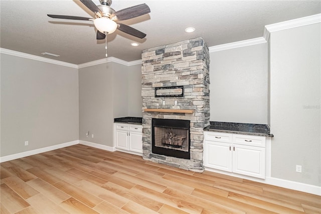 unfurnished living room featuring a fireplace, light wood-type flooring, a textured ceiling, ceiling fan, and ornamental molding