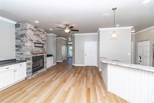 kitchen with ceiling fan, decorative light fixtures, white cabinetry, dark stone counters, and light hardwood / wood-style floors