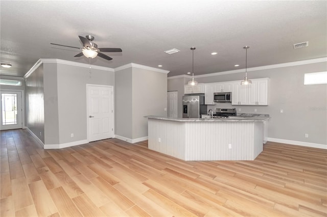 kitchen featuring decorative light fixtures, appliances with stainless steel finishes, white cabinets, and light hardwood / wood-style flooring