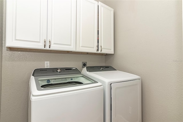 laundry area with separate washer and dryer and cabinets