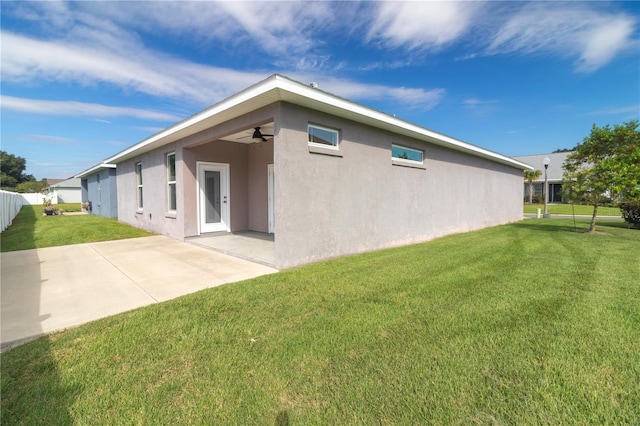 back of property featuring ceiling fan, a lawn, and a patio area