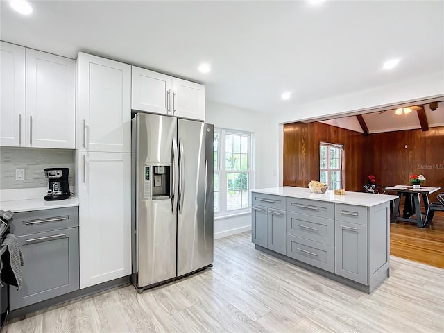 kitchen with beamed ceiling, wooden walls, stainless steel fridge with ice dispenser, white cabinetry, and gray cabinets