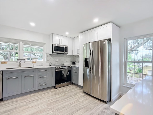 kitchen featuring appliances with stainless steel finishes, white cabinets, gray cabinets, sink, and plenty of natural light