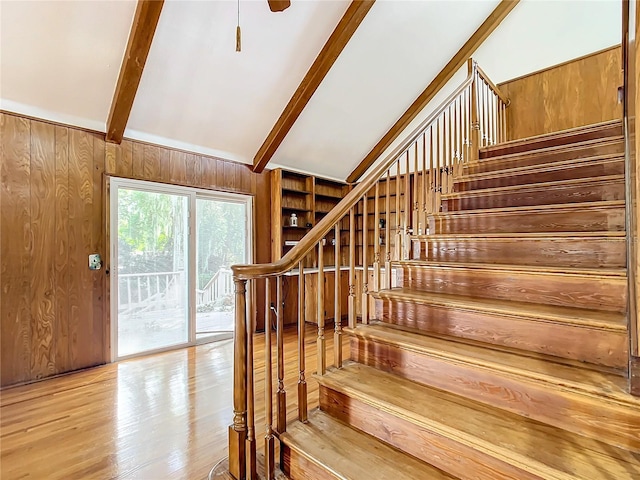 staircase with hardwood / wood-style flooring, wooden walls, and lofted ceiling with beams