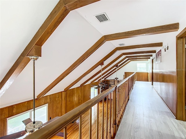 hallway with vaulted ceiling with beams, light hardwood / wood-style floors, and wooden walls