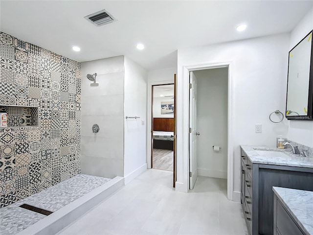 bathroom with a tile shower and vanity