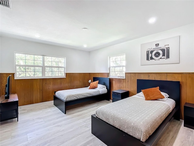 bedroom with light hardwood / wood-style floors and wood walls