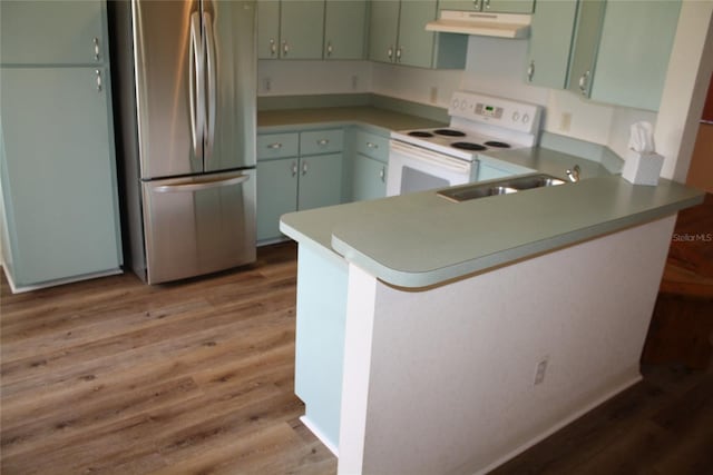 kitchen with light hardwood / wood-style floors, stainless steel refrigerator, kitchen peninsula, white range with electric stovetop, and sink