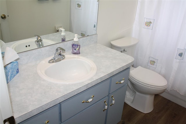 bathroom with wood-type flooring, vanity, walk in shower, and toilet