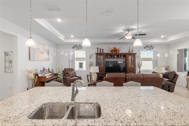 kitchen featuring pendant lighting, sink, a tray ceiling, and light stone countertops