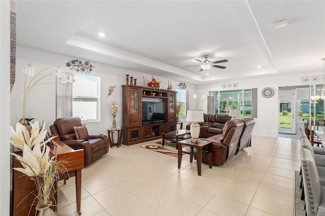 living room with ceiling fan with notable chandelier, a tray ceiling, and crown molding