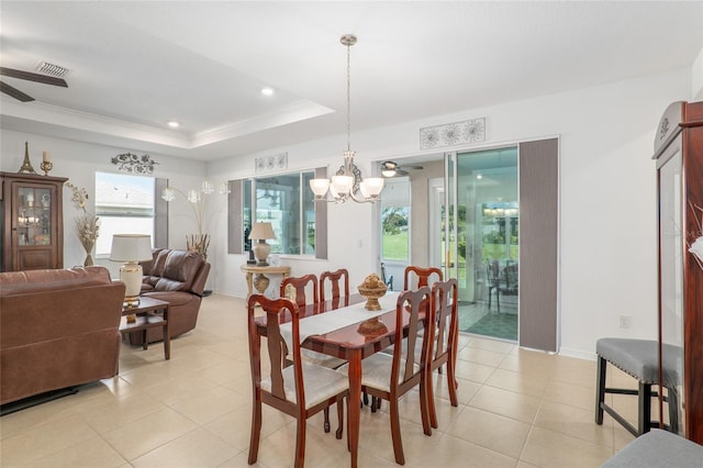 dining room with ceiling fan with notable chandelier, a tray ceiling, light tile patterned flooring, and crown molding