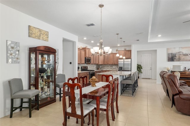 tiled dining room with a notable chandelier and sink