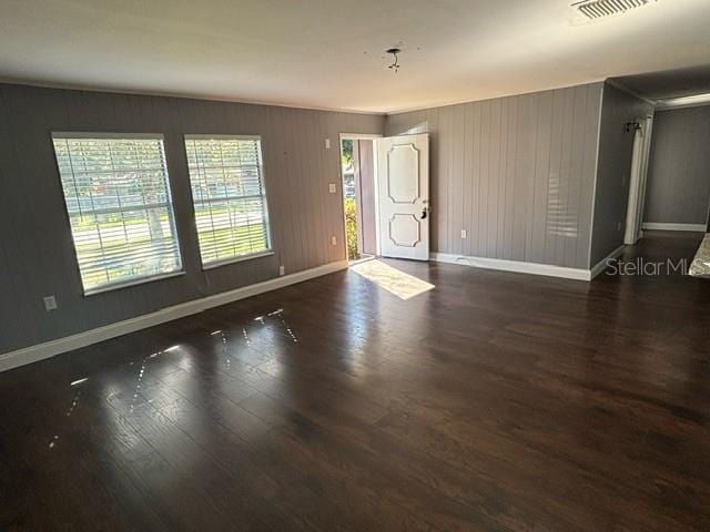 unfurnished room with dark wood-type flooring and wood walls