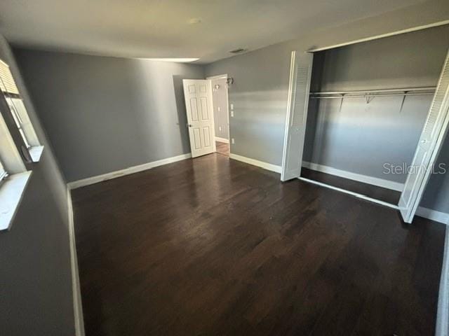 unfurnished bedroom with a closet and dark hardwood / wood-style flooring