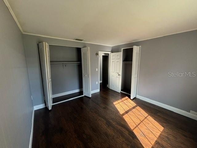 unfurnished bedroom with ornamental molding and dark hardwood / wood-style flooring