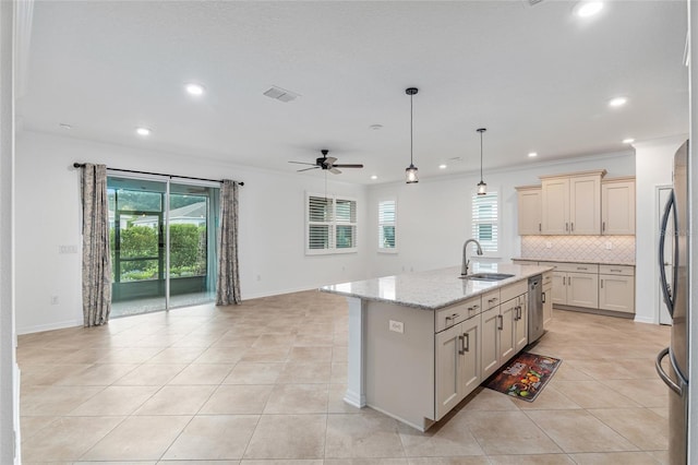 kitchen with crown molding, sink, an island with sink, and light stone counters