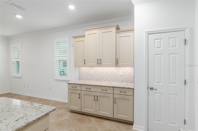 kitchen with cream cabinetry, light tile patterned flooring, tasteful backsplash, light stone countertops, and crown molding