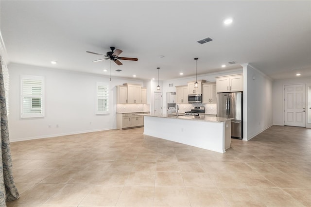 kitchen featuring hanging light fixtures, a kitchen island with sink, backsplash, appliances with stainless steel finishes, and light stone countertops