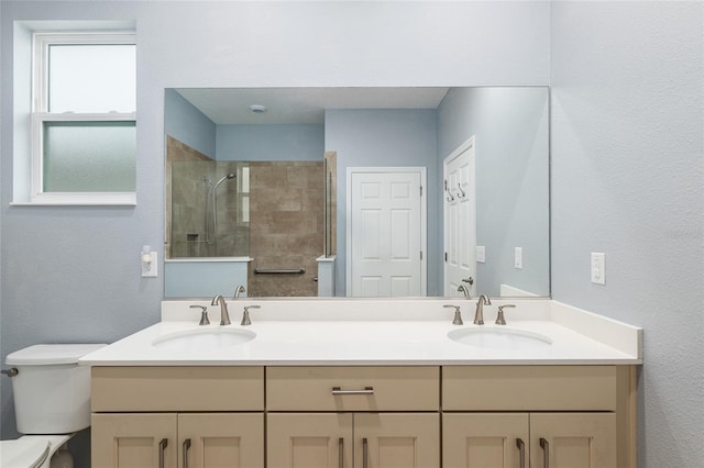 bathroom with tiled shower, vanity, and toilet