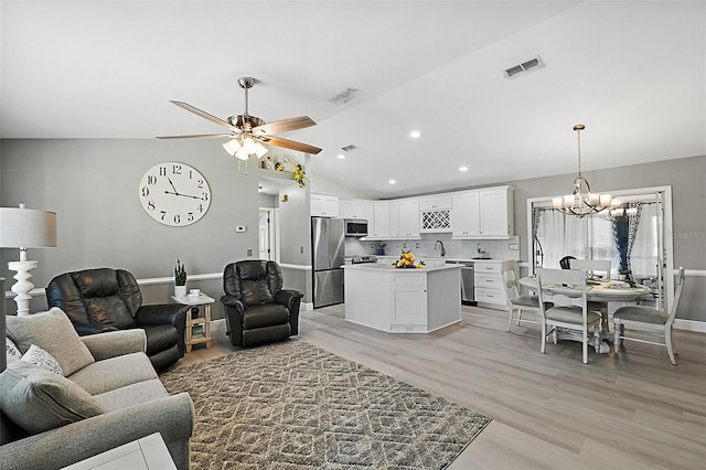 living room featuring sink, ceiling fan with notable chandelier, vaulted ceiling, and light wood-type flooring