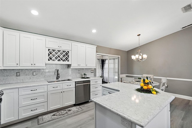 kitchen with pendant lighting, a center island, sink, stainless steel dishwasher, and white cabinetry