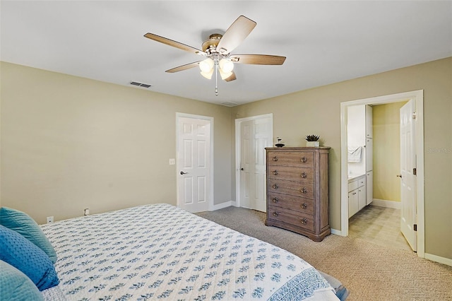 bedroom featuring light carpet, ensuite bathroom, and ceiling fan