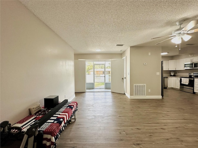 living room with ceiling fan, a textured ceiling, and hardwood / wood-style floors