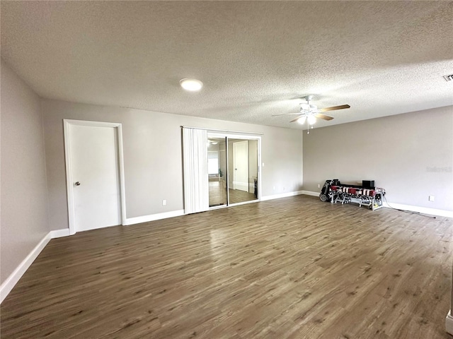 unfurnished room featuring a textured ceiling, ceiling fan, and dark hardwood / wood-style flooring