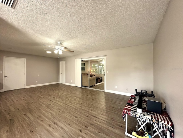 unfurnished room with ceiling fan, a textured ceiling, and dark wood-type flooring