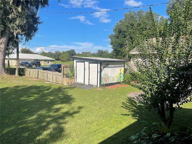 view of yard featuring fence, an outbuilding, and a shed