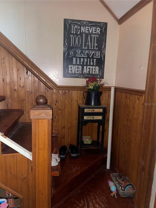 staircase with wood walls and vaulted ceiling