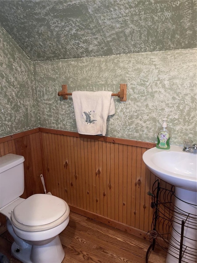 bathroom with a wainscoted wall, wallpapered walls, toilet, and wood finished floors