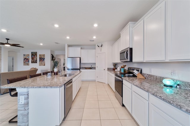 kitchen featuring a kitchen island with sink, stainless steel appliances, sink, and a breakfast bar