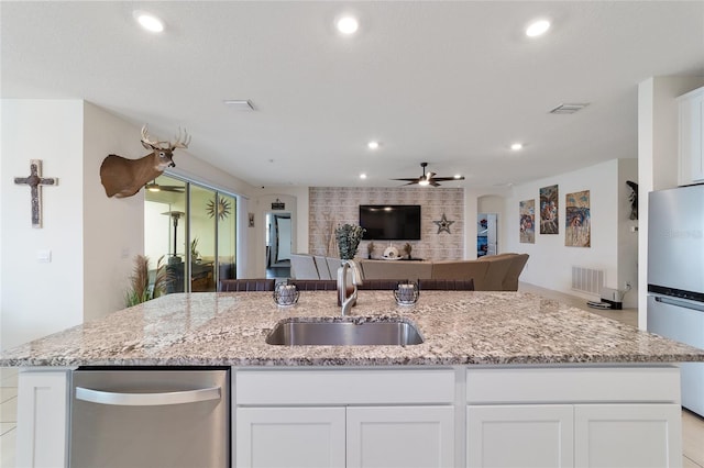 kitchen with white refrigerator, light stone countertops, sink, and white cabinetry