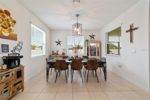 dining area with a notable chandelier, light tile patterned floors, and a wealth of natural light