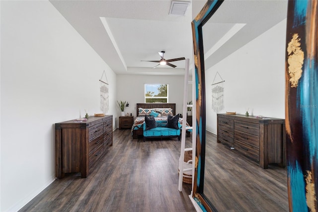 bedroom with ceiling fan, a raised ceiling, and dark hardwood / wood-style floors