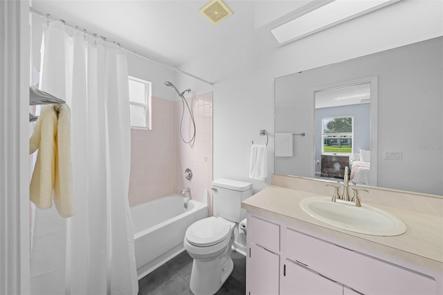 full bathroom with vanity, tile patterned floors, a skylight, toilet, and shower / bath combo with shower curtain