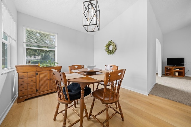 dining area with light wood-type flooring, vaulted ceiling, and a healthy amount of sunlight