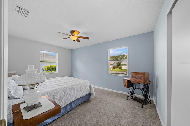 carpeted bedroom with a textured ceiling, multiple windows, and ceiling fan