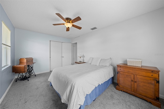 bedroom featuring ceiling fan, a closet, light carpet, and a textured ceiling