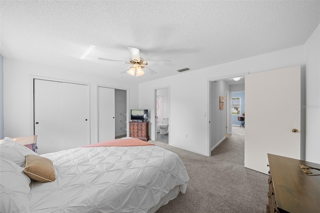 carpeted bedroom with ensuite bath, ceiling fan, two closets, and a textured ceiling