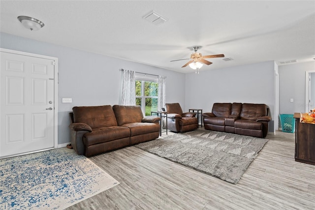 living room with ceiling fan, a textured ceiling, and light wood-type flooring