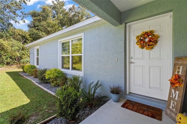 property entrance featuring a lawn