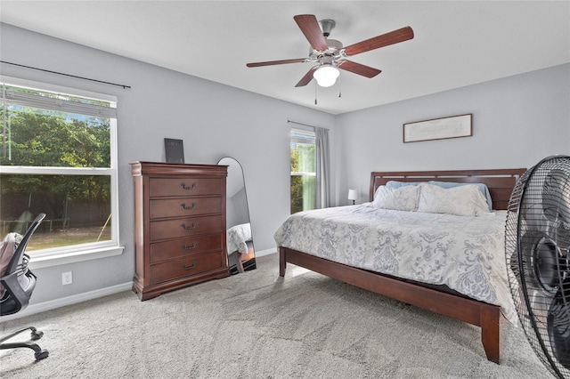 bedroom featuring ceiling fan, light colored carpet, and multiple windows