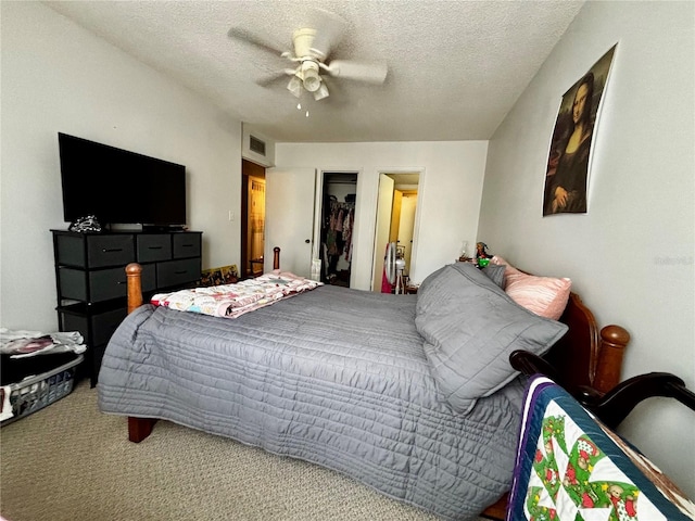 carpeted bedroom with a textured ceiling, ceiling fan, and a closet